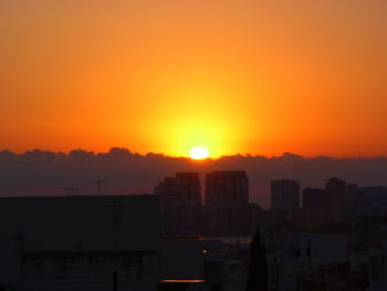 Silhouette buildings against sky during sunset