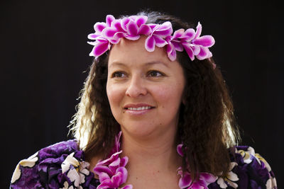 Close-up portrait of smiling young woman against black background