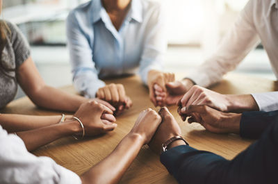 Midsection of business people stacking hands