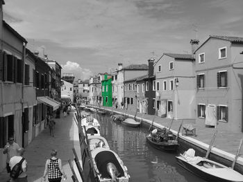 Boats moored in canal amidst buildings in city against sky