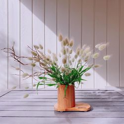 Flower vase on table against white wall