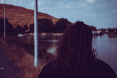 Rear view of woman looking at lake against sky