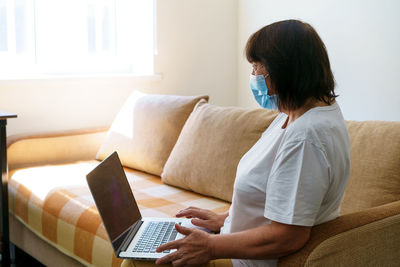 Midsection of woman using phone while sitting on sofa at home