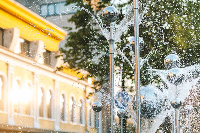 Fountain by building in city during winter