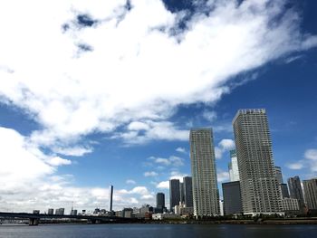 Low angle view of skyscrapers against cloudy sky