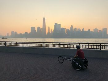 Man riding motorcycle on building in city against sky