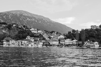 Houses by lake against sky