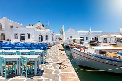 Boats moored by empty chairs at harbor