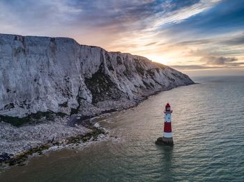 Scenic view of lighthouse by sea against sky during sunset