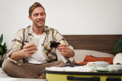 Portrait of smiling friends using mobile phone while sitting at home
