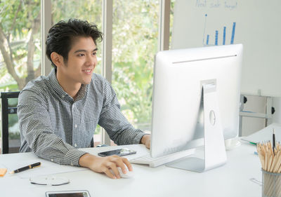 Young man using mobile phone while sitting on table