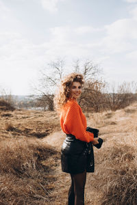 Portrait of young woman standing against sky