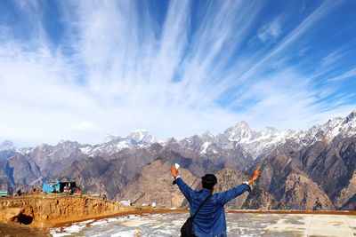 Rear view of man standing on snow covered mountain