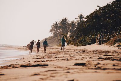 People walking on beach against clear sky