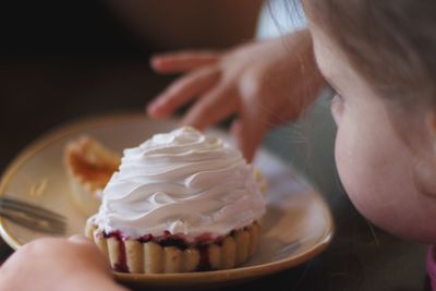 Close-up of girl's hand holding cupcake on table