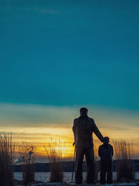 Rear view of silhouette statue standing against sky during sunset