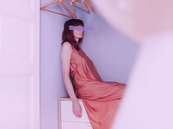 Young woman wearing mask against wall