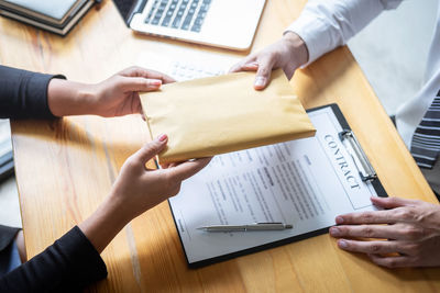 Cropped hands of businesswoman bribing businessman in office