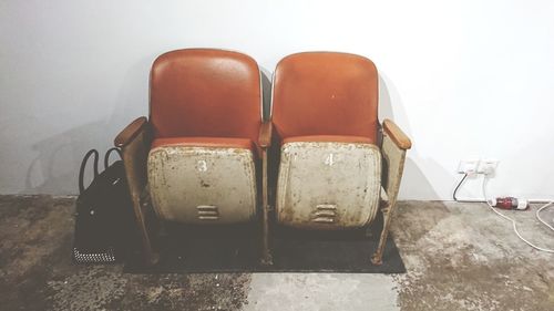 Close-up of empty chairs against wall at home