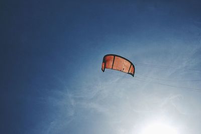 Low angle view of person paragliding against blue sky