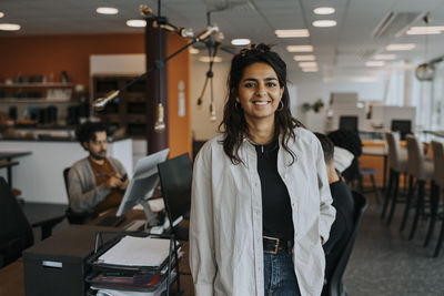 Portrait of smiling young businesswoman standing at corporate office