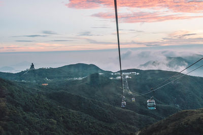 Overhead cable car over mountains against sky