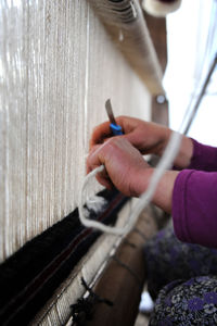 Cropped hands of woman weaving carpet