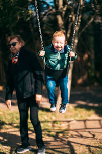 Portrait of little boy swinging with grandmother