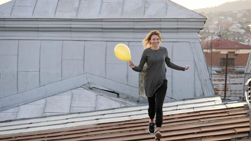 Woman running on roof during sunset