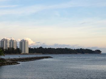 Scenic view of sea by buildings against sky during sunset