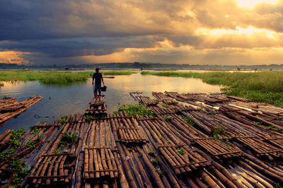 Full length of man on lake against sky during sunset