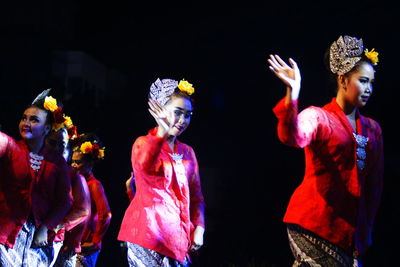 Group of people dancing against black background