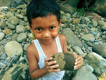 Portrait of cute boy holding rock