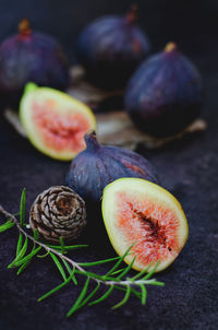 Fresh purple ripe figs with herbs lie on the dark background.