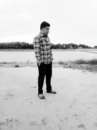 Full length of boy standing on shore against sky