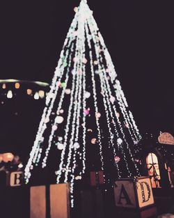 Low angle view of illuminated christmas tree against sky at night