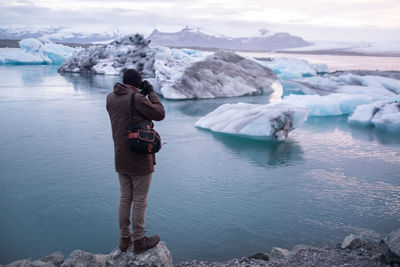 Man standing in lake against sky during winter