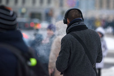 Rear view of people standing on street in winter