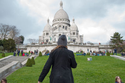 Rear view of woman standing on field against montmartre and sky