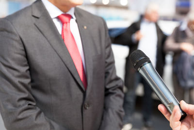 Cropped image of person holding microphone while interviewing businessman