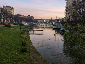 River by buildings against sky during sunset