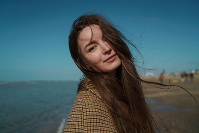 Portrait of beautiful young woman against sky