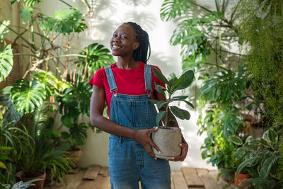 Young woman standing against plants