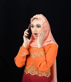 Young woman standing against black background