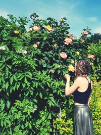 Rear view of woman standing by flowering plants