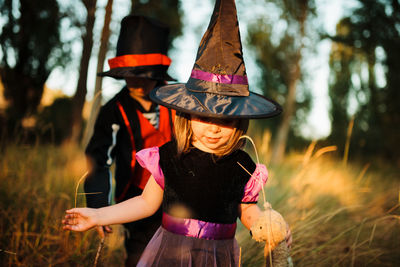 Girl with brother wearing costume during halloween at forest