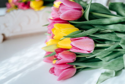 Fresh spring yellow and pink tulips bouquet on white wood table background with copy space for text.