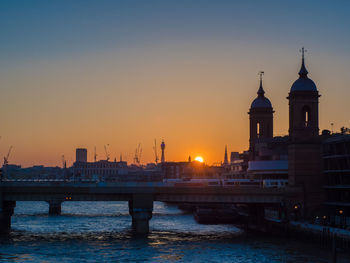 View of buildings at waterfront against sky during sunset