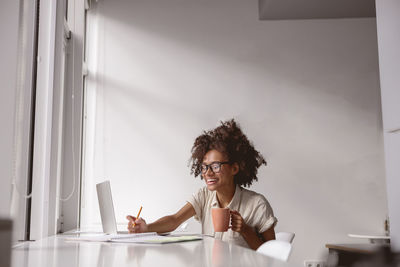 Side view of young woman sitting at home