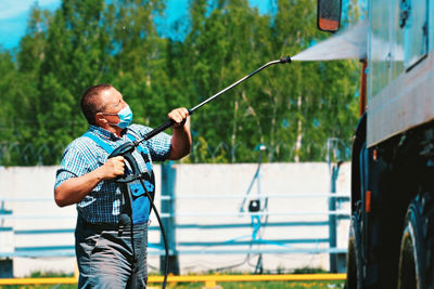 Car wash for special equipment and trucks. a male driver wearing a medical mask